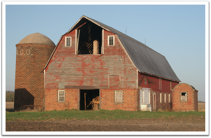 The barn built in 1925 by Gust Wiberg of Trail for Ole K Flateland. A foundation six feet deep was necessary to get below the frost line and the foresight to use tile blocks for the lower eight feet kept it from succumbing to rot. In this photo from 2006, the building is being used to store machinery and it appears to still be structurally sound.