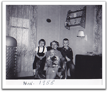 Bonnie Brekke, grandma Maggie Van Tassel, Byron,  and Myles, held by Maggie, November, 1955,  in southeast corner of Oscar & Helen’s living room.