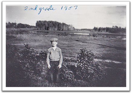 Byron on his first day of school, second grade, September, 1957. The woods in the back are the trees he tried to reach in his ill-fated walk a year or two earlier when he got stuck in the mud.